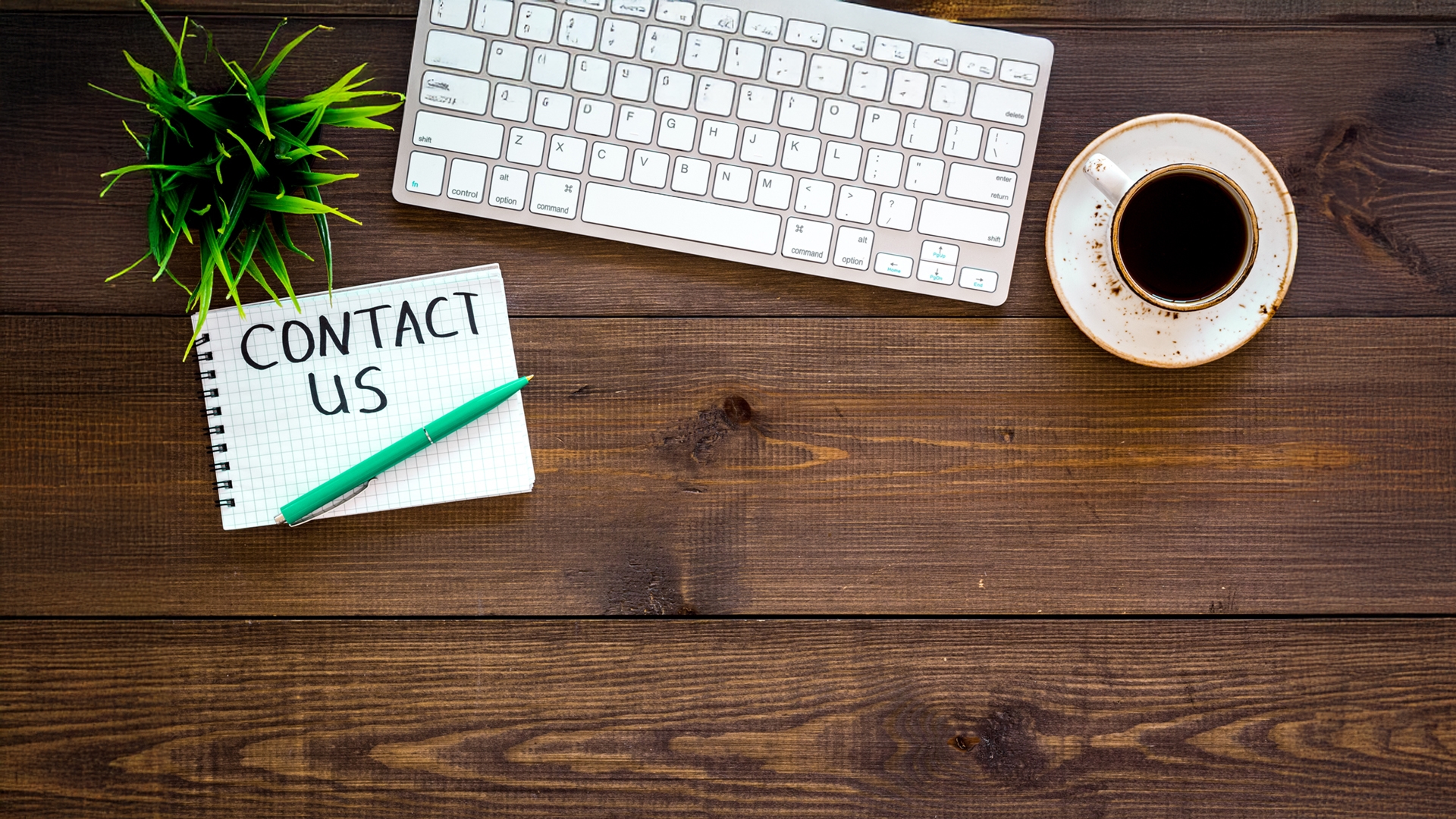 table for contacts, background for contact information. Lettering Contact us in notebook on office work desk with computer on dark wooden background