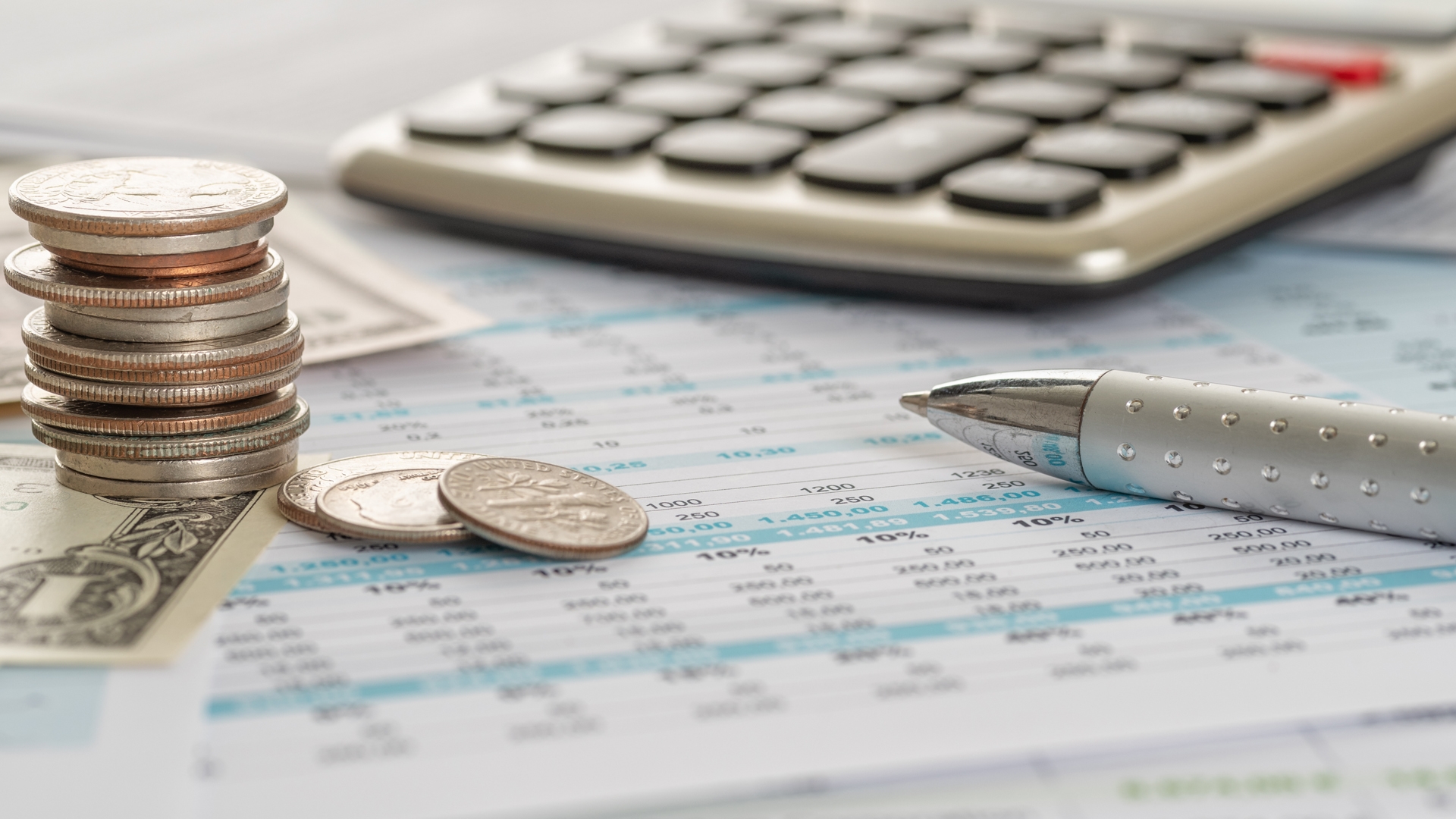 Dollar bills and coins on documents with a calculator