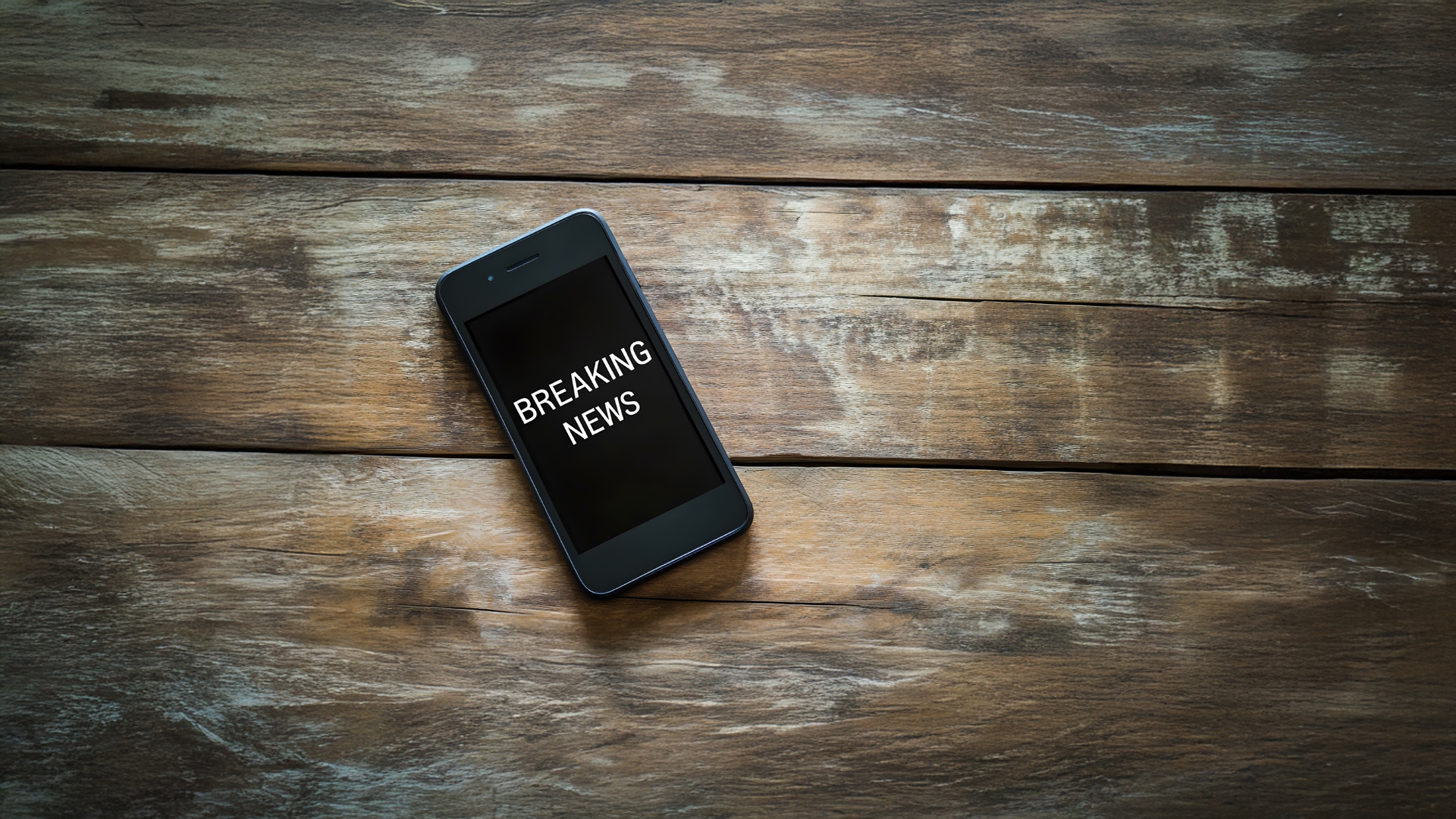 mobile phone on the table with Breaking News on the screen 